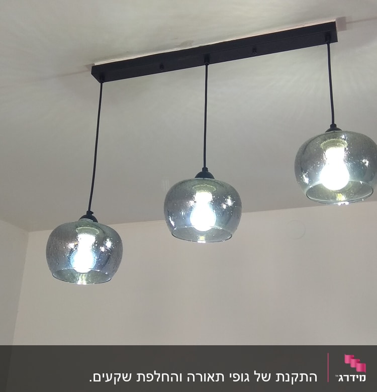 שלושה גופי תאורה תלויים עם נורות דולקות